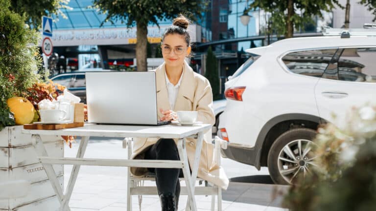 Femme qui fait du télétravail avec sa voiture de location derrière