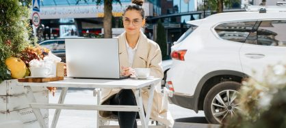 Femme qui fait du télétravail avec sa voiture de location derrière